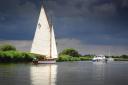 Storm clouds gather as boats sail on the Norfolk Broads at Ludham