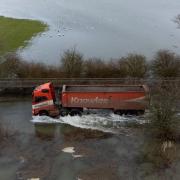 Vehicles navigating the flooded Sutton Gault Causeway.