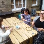 Children making floral crowns fit for a Rose Queen from artificial flowers on Saturday.