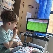 Hunter Martin, aged six, watches football in his hospital room