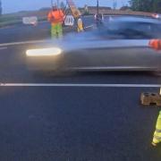 The driver continues travelling at speed on the closed-off road narrowly missing a contractor